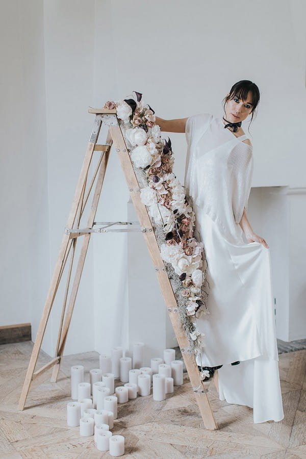 Bride standing on ladder covered in flowers