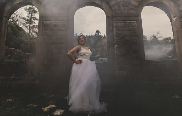 Bride by arch surrounded by smoke