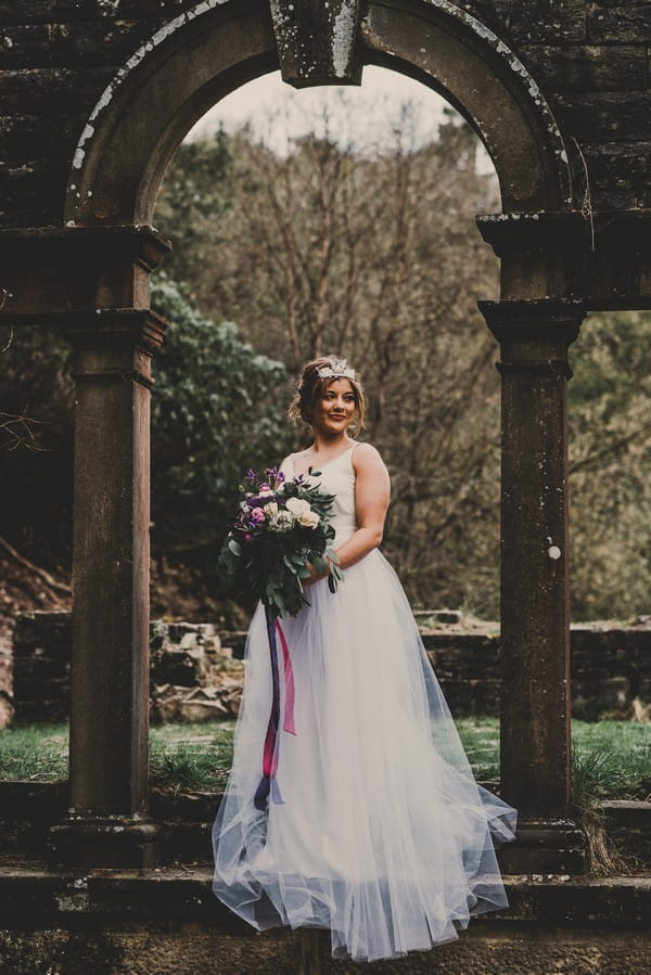 Bride holding bouquet standing by pillars