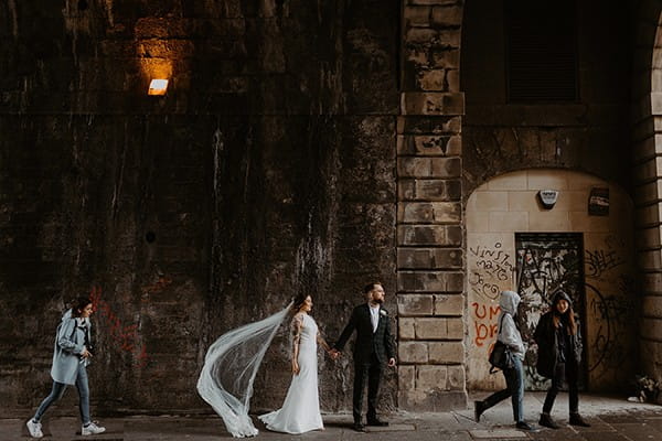 Bride and groom holding hands on path in urban area - Picture by The Hendrys Photography