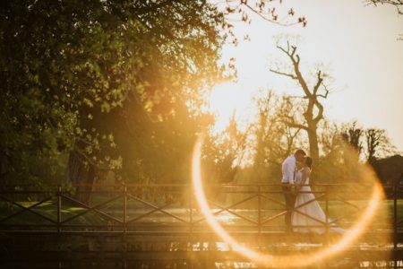 Picture of bride and groom kissing on bridge with glare of sun on lens - Picture by Lee Dann Photography