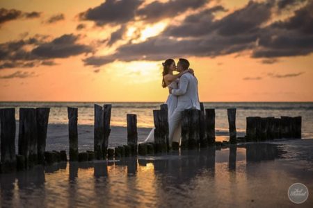 Bride and groom kissing on beach by sea at sunset - Picture by That Moment Photo