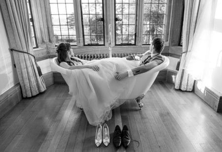 Bride and groom sitting in bath looking out of window - Picture by Copper and Blossom