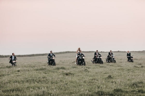 Bride, groom and groomsmen riding motorbikes across a field - Picture by Ben Wigglesworth Photography