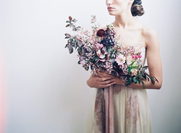 Bride holding large bouquet with mauve and blush flowers and foliage