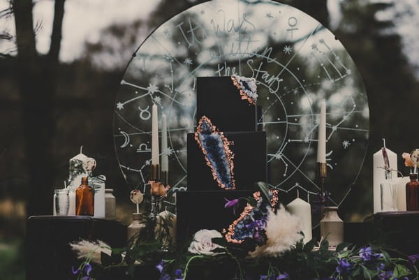 Black wedding cake with geode detail on table with celestial items