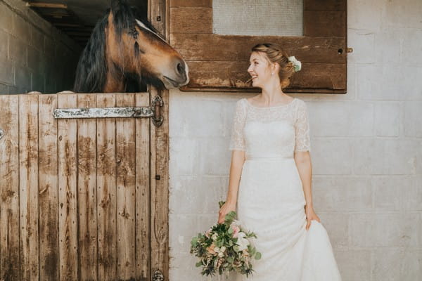 Bride standing next to horse in stable