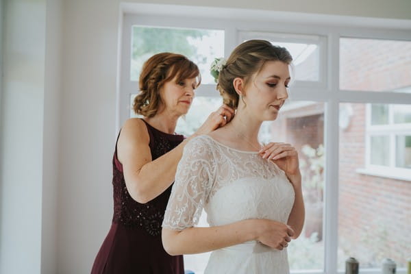 Bride's mother fastening bride's necklace