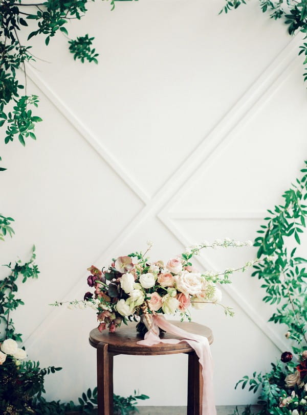 Wedding bouquet n small table in front of foliage backdrop