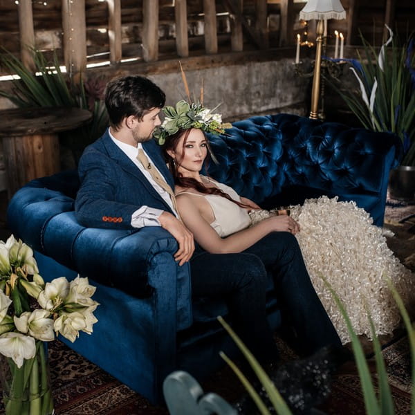 Bride and groom sitting on blue Chesterfield sofa available to hire from from The Prop Factory