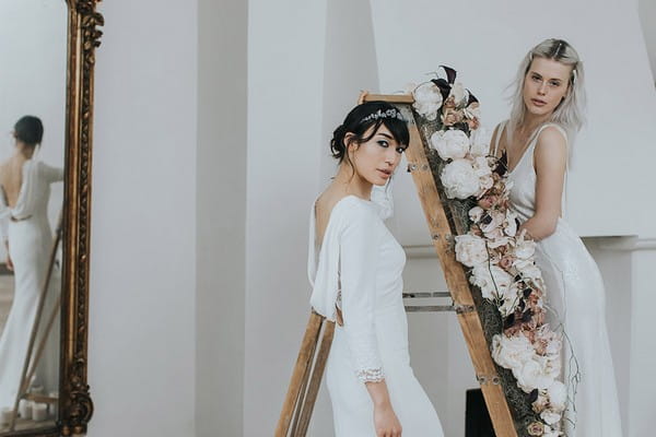 Two brides by ladder covered in flowers