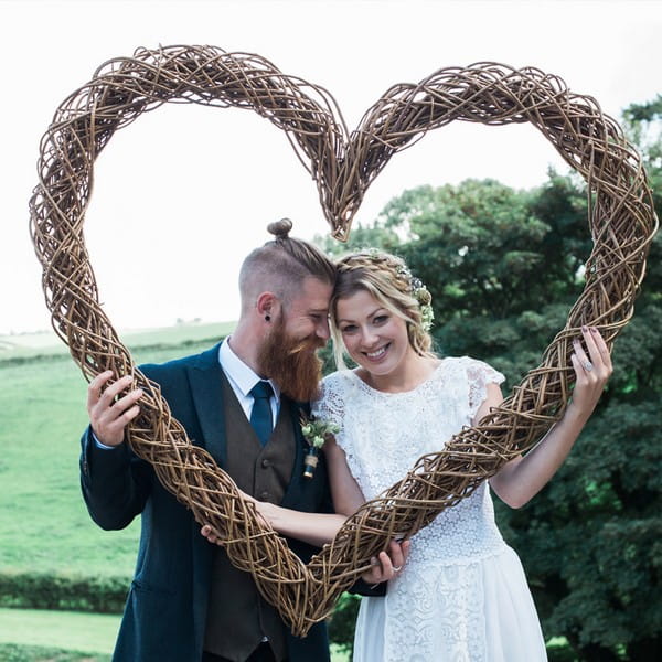 Bride and groom holding up willow heart available to hire from from The Prop Factory