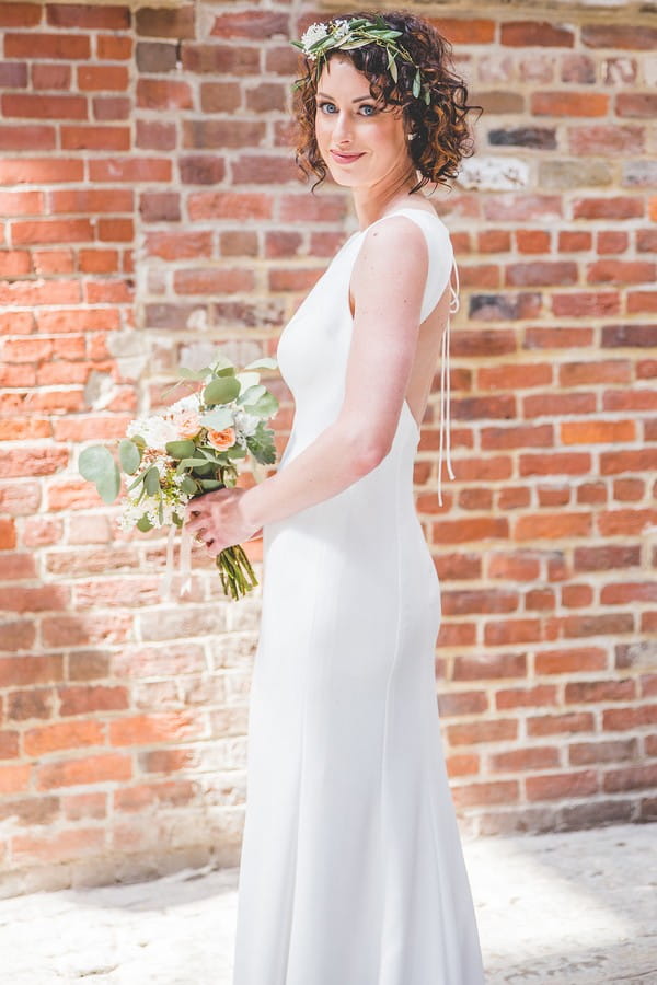 Bride holding bouquet in front of brick wall