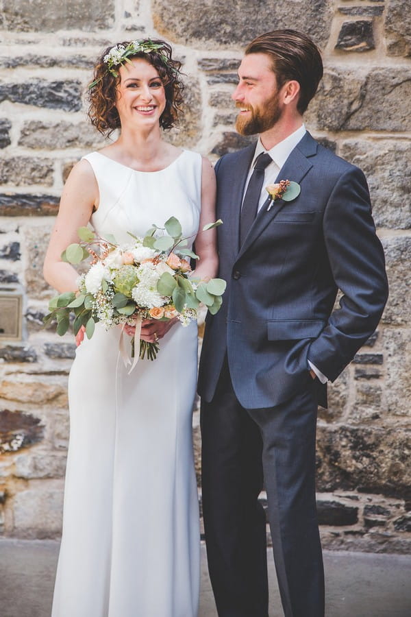 Bride and groom standing in front of brick wall