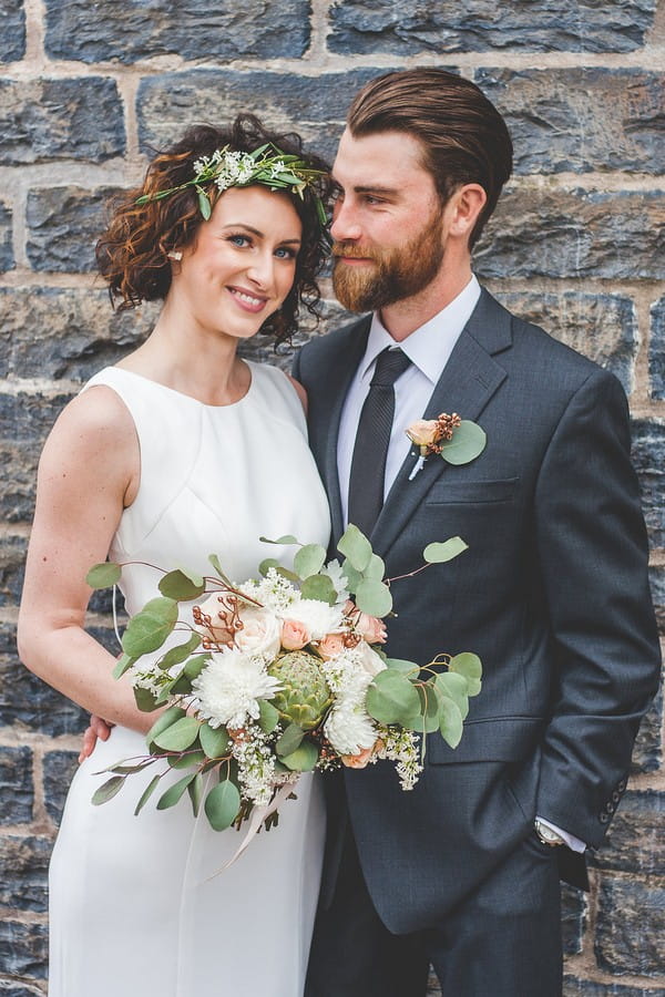 Bride holding bouquet next to groom