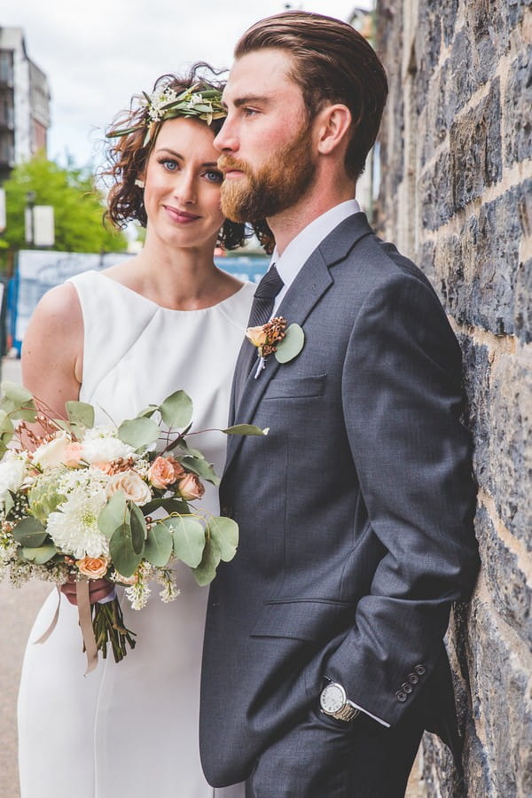 Bride and groom standing against brick wall