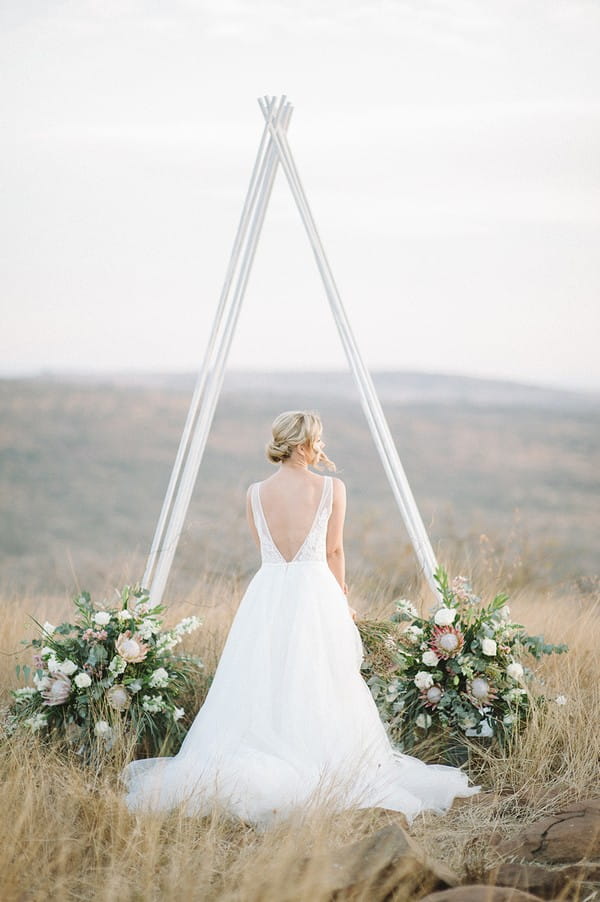 Bride standing in front of tipi style ceremony arch