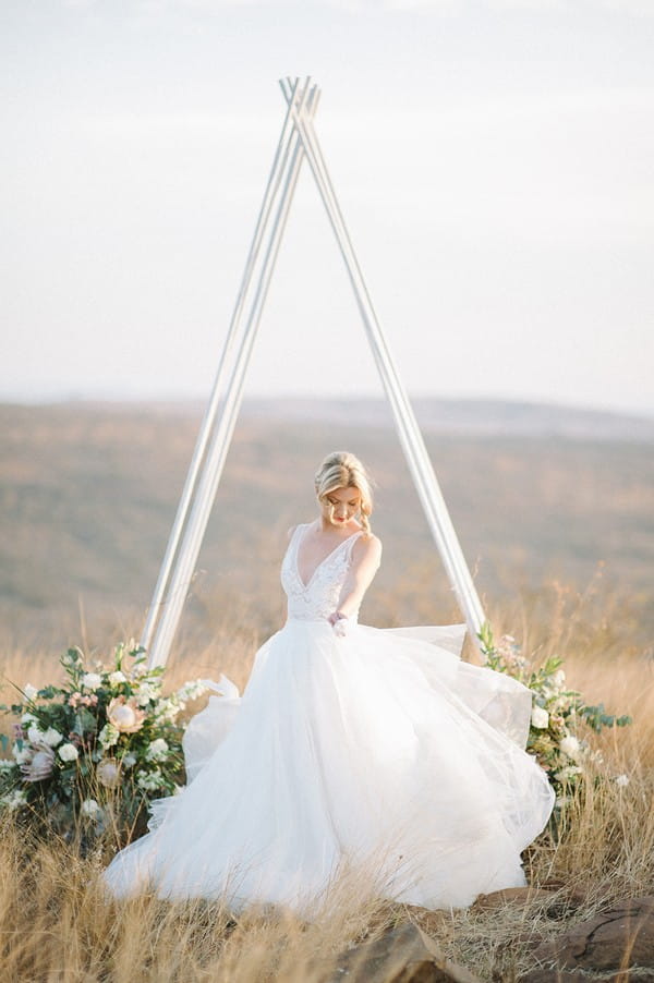 Bride twirling in front of tipi style ceremony arch