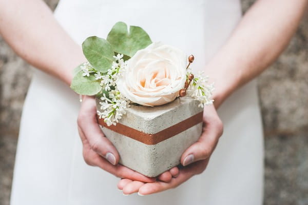 Bride holding concrete pot with flower in it