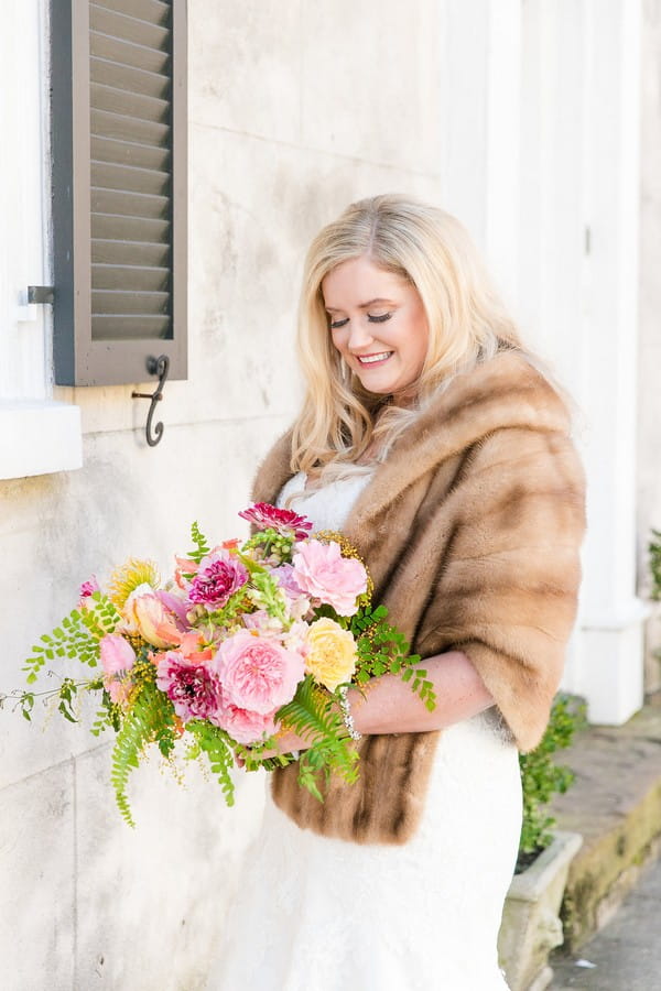 Bride with fur shrug holding colourful bouquet