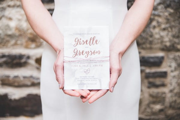 Bride holding wedding invitation with copper writing