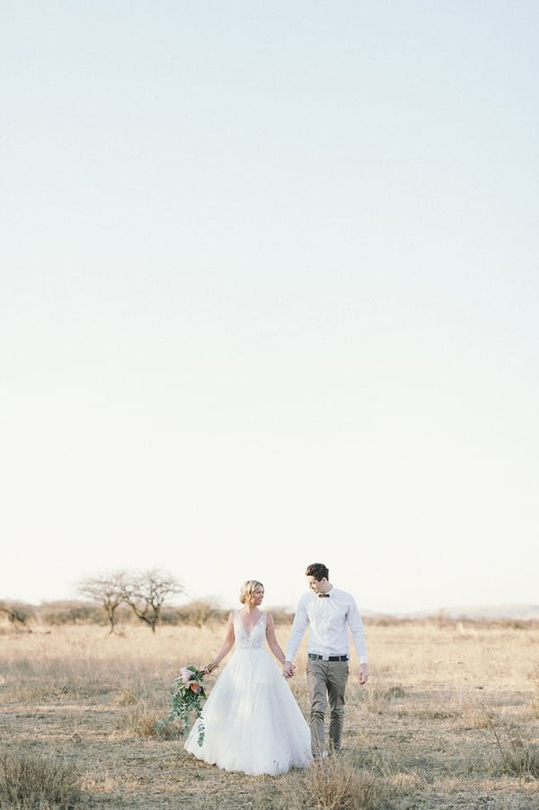 Bride and groom walking across Nambiti Private Game Reserve