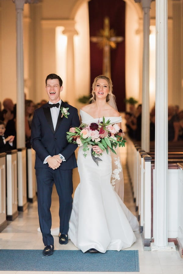 Groom with big smile as he leaves wedding ceremony with bride