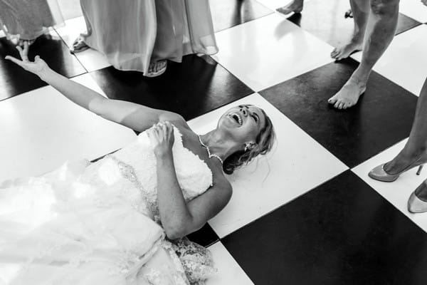 Bride lying on dance floor laughing - Picture by Louise Adby Photography