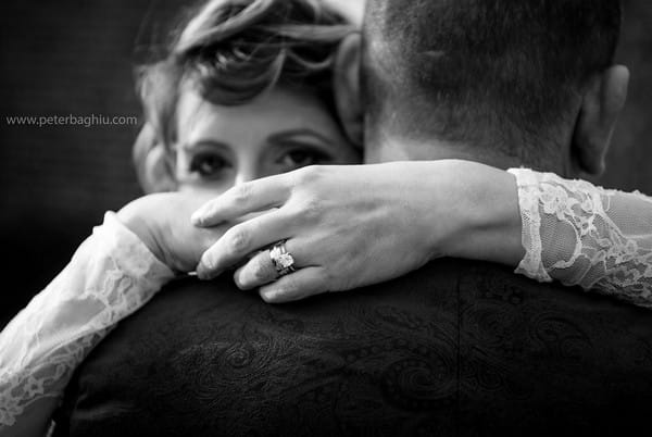 Bride looking over groom's shoulder as she hugs him - Picture by Peter Baghiu Photography