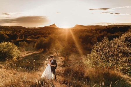 Bride and groom with sun setting in background between two hills - Picture by Andy Gaines Photography
