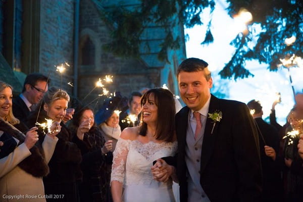 Bride and groom walking holding hands past wedding guests with sparklers - Rosie Cutbill Photography