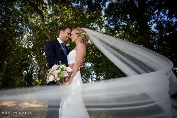 Bride and groom touching heads as bride's veil blows around them - Martin Dabek Photography