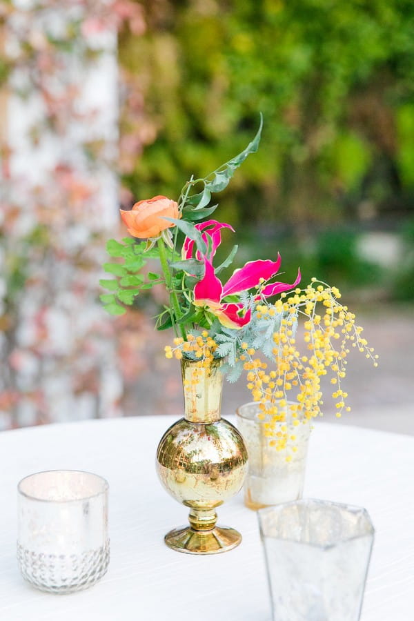 Small gold vase of colourful wedding flowers