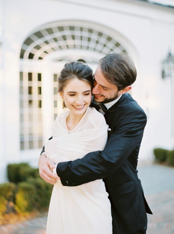 Groom hugging bride from behind