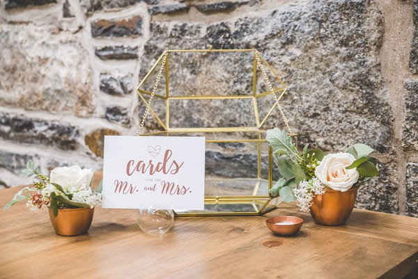 Geometric wire wedding card holder surrounded by copper pots