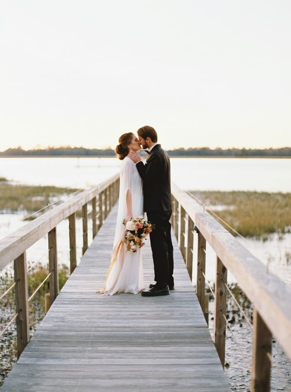 Bride and groom kissing on wooden bridge