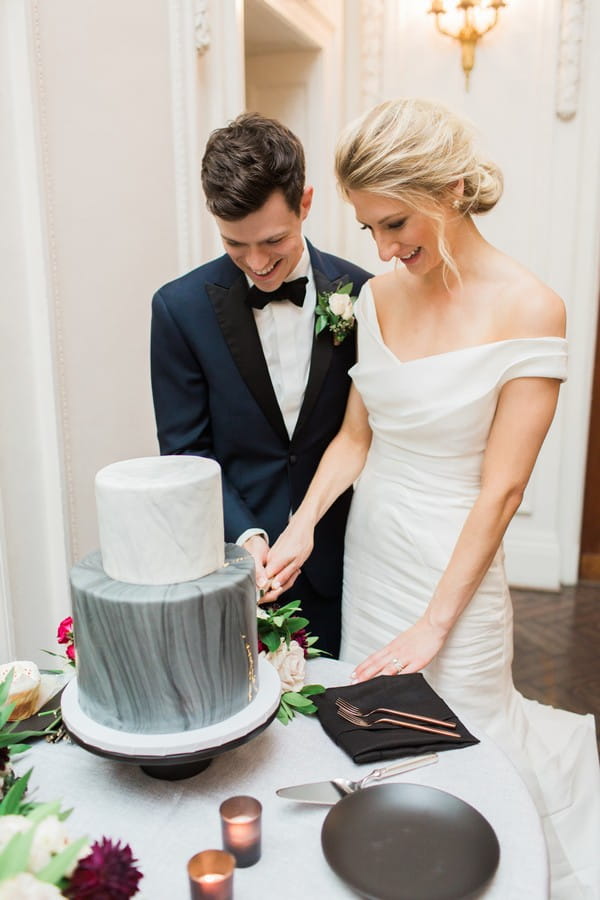 Bride and groom cutting marble effect wedding cake