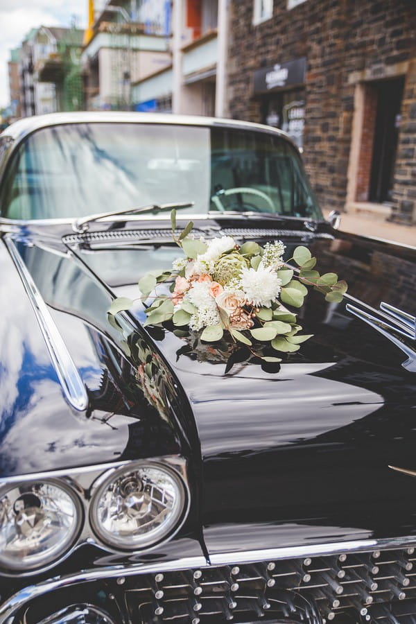 Bridal bouquet on bonnet of Cadillac wedding car