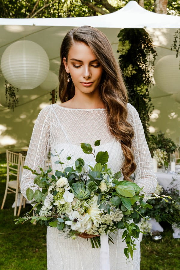 Bride holding bouquet of foliage and white flowers