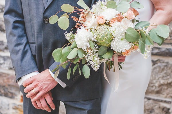 Artichoke, green foliage and white and peach flowers in bride's bouquet