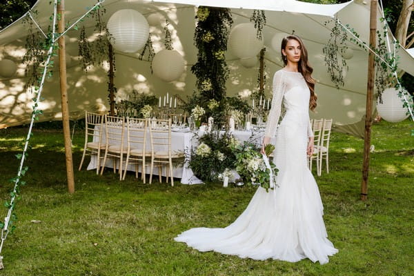 Bride standing in front of stretch tent with wedding table under it