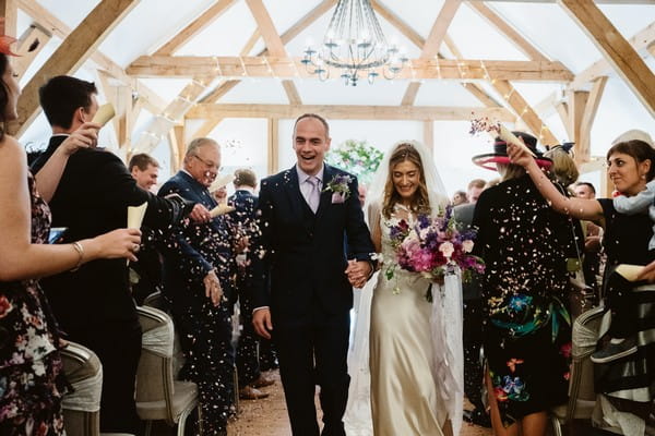 Couple leaving wedding ceremony at Sandhole Oak Barn