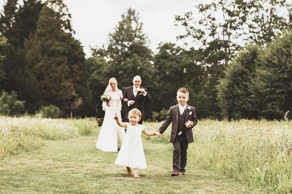 Flower girl and pageboy walking in front of bride