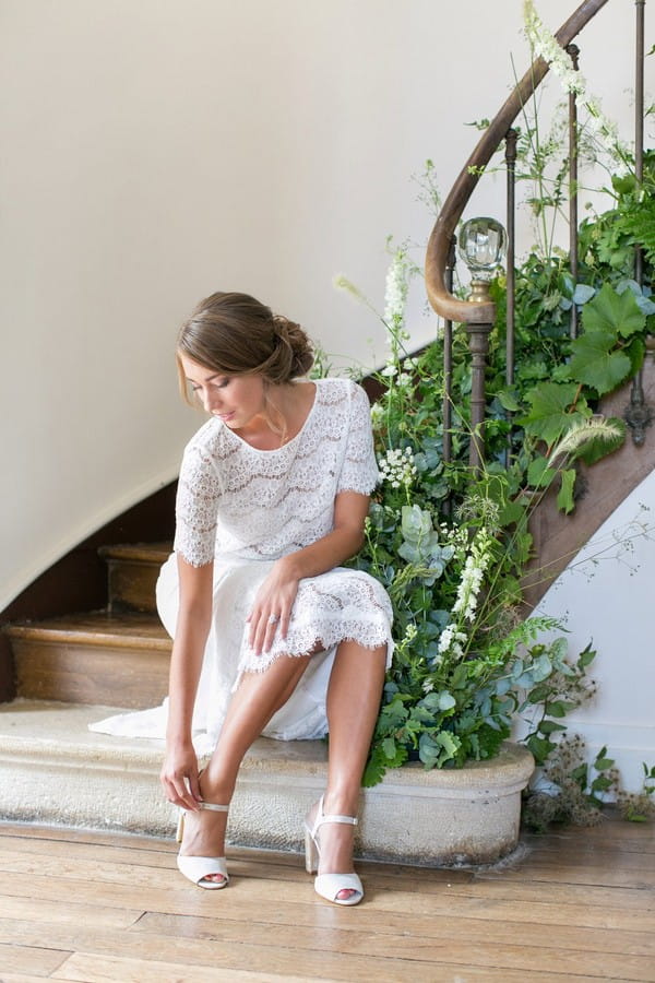 Bride sitting on stairs putting fastening shoe