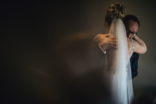 Groom looking over bride's shoulder as they hug - Picture by Sean O'Dell Photography