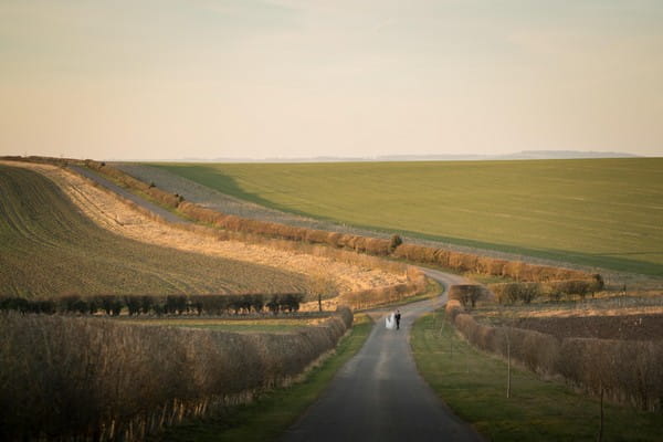 Bride and groom walking down middle of country road - Picture by Linus Moran Photography