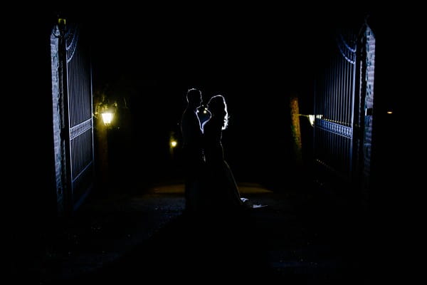 Bride and groom at gates of Casa Bruciata at night - Picture by Rebecca Parsons Photography