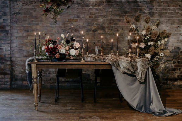 Wedding table with candles, autumnal flower displays and velvet table runner