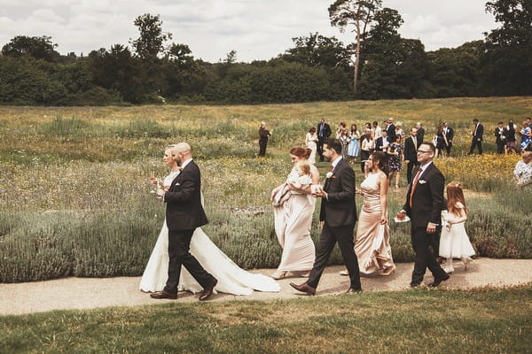 Bride, groom and guests walking down path at Coworth Park
