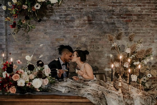 Bride kissing groom on the nose at wedding table